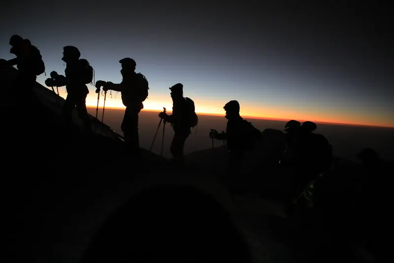Climbers silhouetted against the first light of dawn